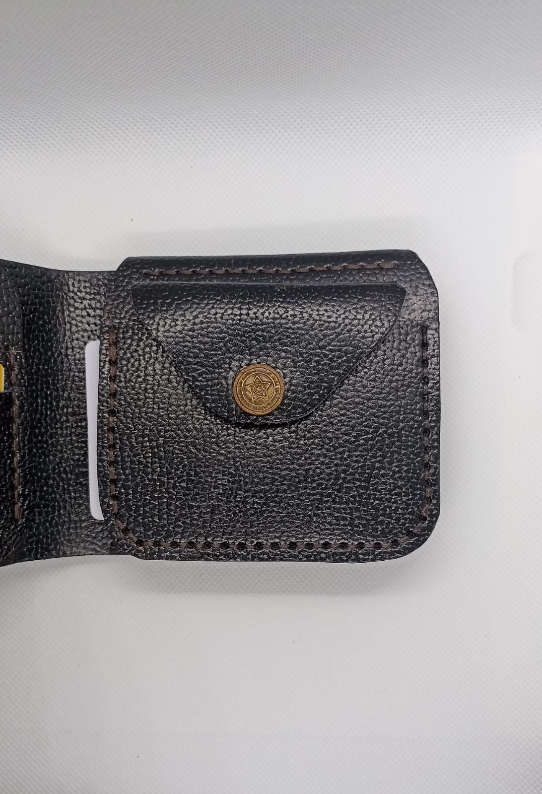 Black leather wallet with a gold button on a light gray background
