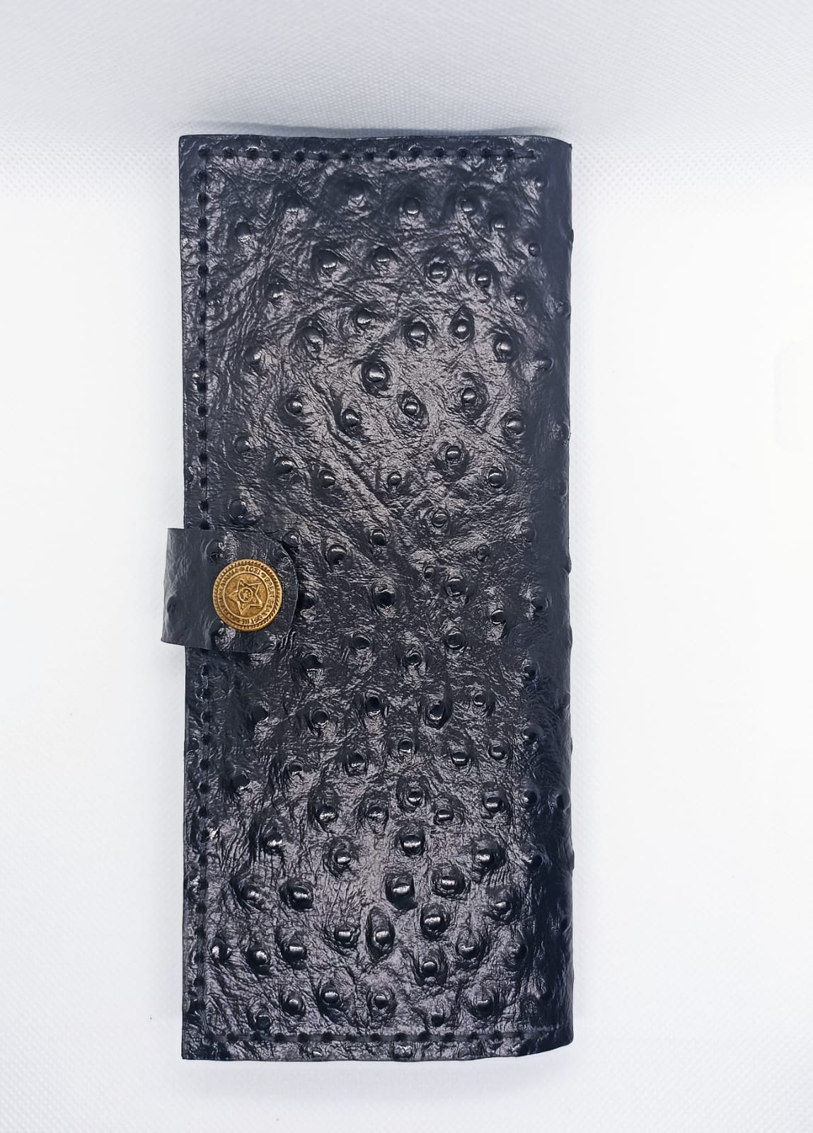 Black textured leather wallet with gold button on a white background